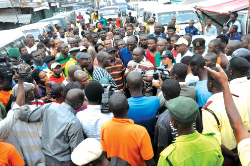 A sanitation offender being taken into the Black Maria. Inset: Government officials addressing residents of Iddo in Lagos Mainland Local Government Area.