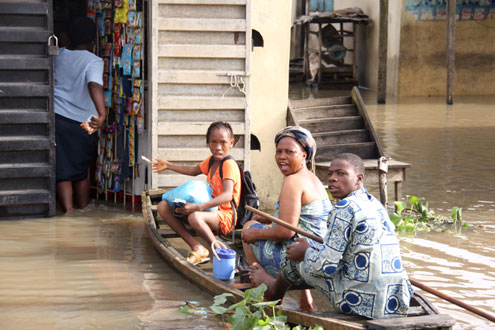 A little girl on her way to school in a canoe, stops to buy something in a flooded house, this morning at Ajegunle, on Ikorodu road, Lagos. PHOTO: IDOWU OGUNLEYE.
