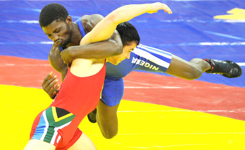 BRONZE EFFORT…Romeo Joseph of Nigeria (blue) wrestles with Marius Loot of South Africa on the way to winning the bronze medal in the 60kg category of the Greco-Roman Wrestling at the 2010 Commonwealth Games in New Delhi yesterday. PHOTO: AFP.