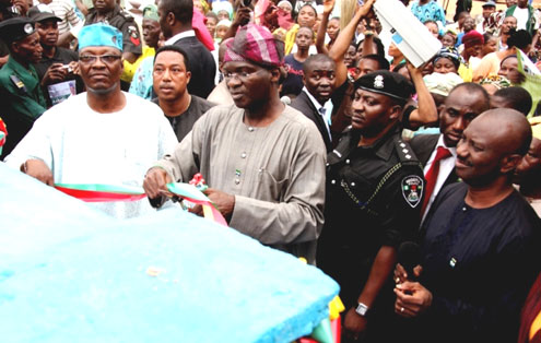 Fashola (left) cutting the tape for a rural electrification project with the Commissioner for Rural Development, Prince Lanre Balogun.