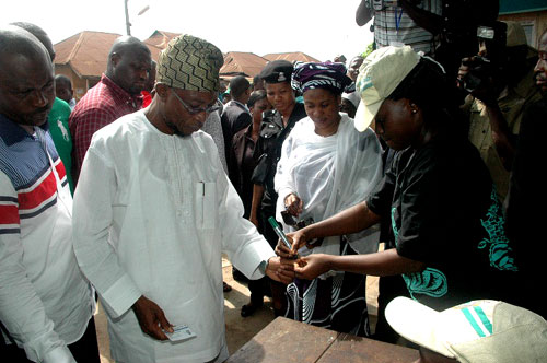 Osun State Governor, Ogbeni Rauf Aregbesola and his wife, Serifat (Middle) engaging in accreditation at Unit 1, Ward 8 in Ifofin Area of Ilesa East Local Government, Osun State on Saturday 02-04-2011