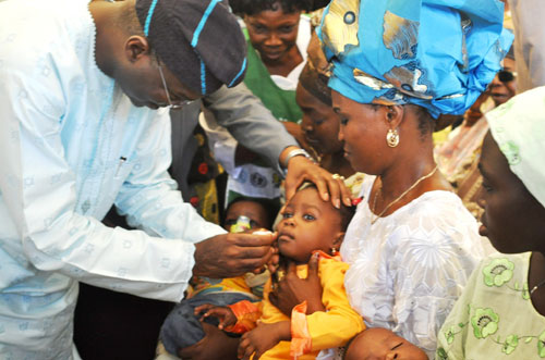 Lagos State Governor,  Mr. Babatunde Fashola SAN (2nd left),   immunizing a child  during the Quartely Sensitization Programme on the  Eradication of Polio of the Nigeria Governorsâ€™ Forum   at the Oshodi Sports Centre (Jalisco) Oshodi Local Government  Secretariat on Saturday August 13, 2011. With him is the Special Adviser to the Governor on Public Health, Dr. (Mrs.) Yewande Adeshina (2nd left), and others .