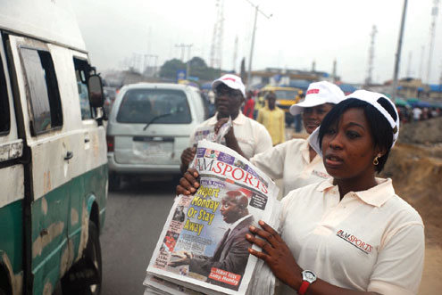 A staff of A.M.Sports displaying the newspaper at Ajah.