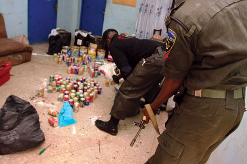 A police bomb disposal expert flanked by an armed policeman packs defused home-made bombs made from cans of soft drink at the bomb disposal unit of the Kano state police command in northern Nigerian city of Kano yesterday. Police said they recovered over 300 undetonated improvised explosive devices in various parts of the city since three days, a day after multiple explosions and gun assaults by Boko haram Islamists on security formations which killed 185 people. AFP PHOTO