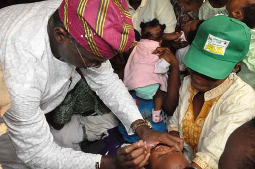 Lagos State Governor, Mr. Babatunde Fashola SAN (left) immunizing a child during the Joint Lagos and Ogun Governors Polio Awareness Day Program with the theme, “Community Leaders Against Polio-CLAP” at Akinde-Ologogoro Community, Ojokoro LCDA, (Lagos State)-Ado-Odo/Ota LGA (Ogun State) on Saturday, February 11, 2012.