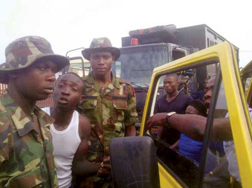 Irate soldiers during the attack on taskforce officials in Lagos, yesterday.