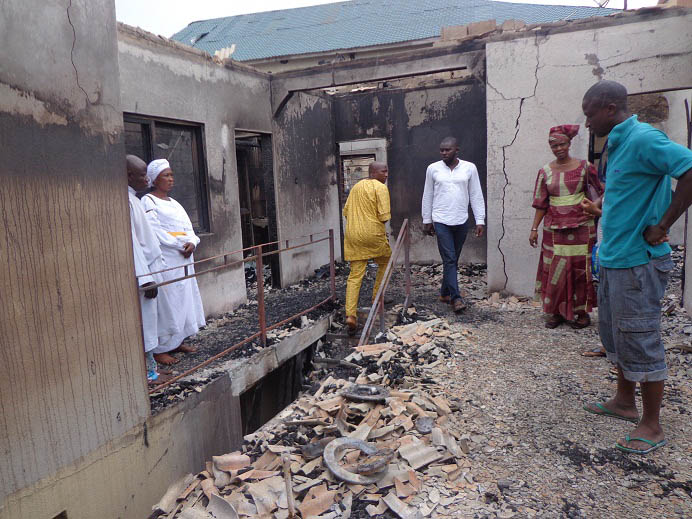 Gbenga Okunowo(right) and some sympathisers at his burnt house oday