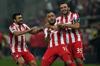 Olympiakos Piraeus Kostas Mitroglou (C) celebrates with teammates after scoring Against Arsenal