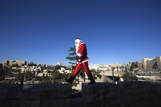 A palestinian man dressed up as santa Claus carries a Christmas tree and rings a bell as he walks along the wall of Jerusalem’s old city. AFP photo