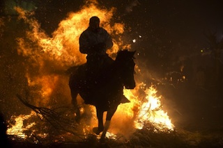 a horse rider jumps over bon fire to signal the feast of  St Anthony
