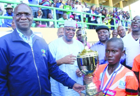 Lagos State Governor, Babatunde Fashola, SAN, (left) presenting the trophy to the captain of Ogedegbe Primary School, Warri, Master Obukowho Sherif (right) during the Channels National Kids Cup final competition at the Teslim Balogun Stadium, Surulere, Lagos, yesterday. With them are Delta State Governor, Dr Emmanuel Uduaghan (2nd right) and the Chairman/Chief Executive Officer of Channels TV, Mr. John Momoh (middle).