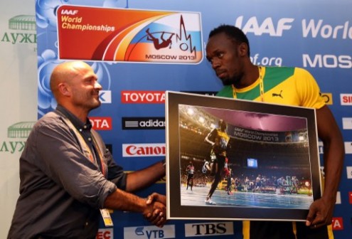 AFP photographer Oliver Morin (L) shakes hands with Jamaica's Usain Bolt as he gives him a print of a picture he took of Bolt during the 100m final prior to a press conference at the Luzhniki stadium in Moscow during the World Athletics Championships.  AFP PHOTO