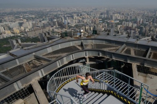 A runner (bottom C) arrives at the top of the China World Summit Wing Hotel before the Beijing skyline during a 'vertical run' event on August 3, 2013. 