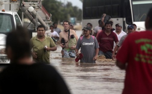 Residents and tourists wade through a flooded street in Acapulco, Guerrero state, Mexico, after heavy rains hit the area on September 16, 2013. AFP