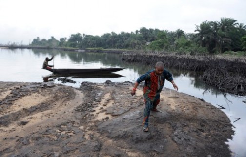 a man walks on slippery spilled crude oil on the shores and in the waters of the Niger Delta swamps of Bodo, a village in the famous Nigerian oil-producing Ogoniland. AFP
