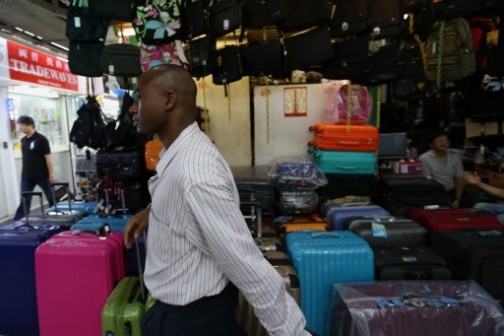 39-year-old trader Ali Diallo from Guinea (front), who sells Chinese electronics to retailers across Africa, walks through Chungking Mansions --  a bustling labyrinth known for budget hotels and no-frills restaurants -- in Hong Kong. 