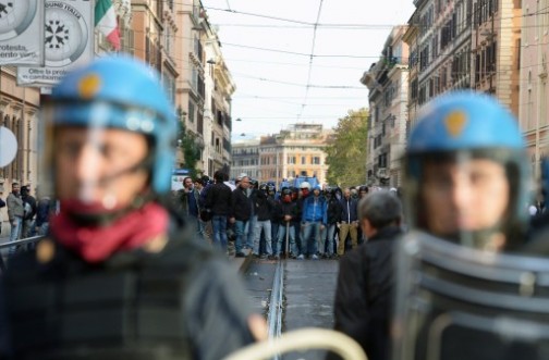 A group of men from the CasaPound (a social center of fascist inspiration) holding batons faces anti-riot policemen as thousands of people march during an anti-austerity protest on October 19, 2013 in Rome. Between 3,000 and 4,000 police officers have been deployed, Italian media reports said, and protest organisers say they expect more than 20,000 to join.    AFP
