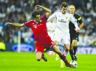 Bayern Munichs Spanish midfielder Javi Martinez (left) blocks Real Madrids Welsh forward Gareth Bale from the ball during the UEFA Champions League semifinal first leg match at the Santiago Bernabeu stadium in Madrid on 23 April, 2014. The two teams play the second leg tonight in Germany. AFP PHOTO.