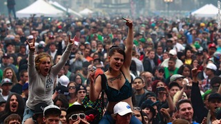 Members of a crowd numbering tens of thousands smoke marijuana and listen to live music, at the Denver 420 pro-marijuana rally at Civic Center Park in Denver