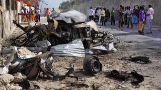 Somalis gather near the wreckage of one of the vehicles used for a car bomb, following a militant attack on the presidential palace in Mogadishu