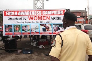 A LASTMA official reads through a banner showing the signs and symptoms of Ebola virus
