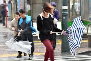 Pedestrians walk against strong wind and rain in Tokyo on October 6