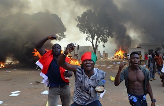 Men shout slogans in front of burning cars, near the Burkina Faso's Parliament where demonstrators set fire, on October 30, 2014