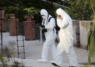 Forensic workers walk near the morgue where stores dead bodies recovered from a mass grave