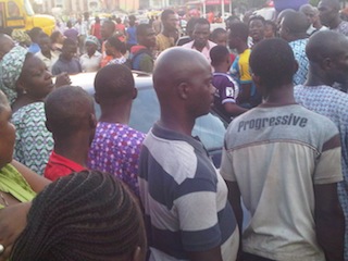People surround the abandoned car at Agege 