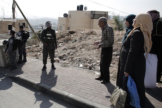 Palestinians speak with Israeli border police standing guard near the Abu Jamal residence