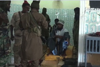 A screengrab taken on November 9, 2014 from a new Boko Haram video released by the Nigerian Islamist extremist group Boko Haram and obtained by AFP shows the leader of the Nigerian Islamist extremist group Boko Haram, Abubakar Shekau (C, down), just before preaching to locals in an unidentified town. 