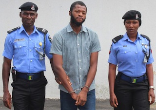 Jeffery Okafor (middle) arrested by Nigerian policemen for murder in the UK
