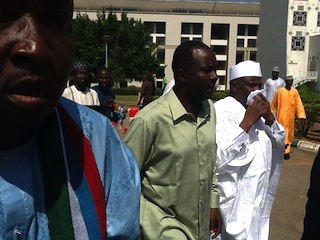 Speaker of the House of Reps, Aminu Tambuwal (R) puts a handkerchief over his nose after being teargassed by policemen