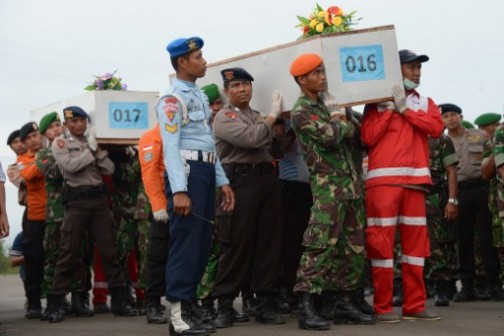 Indonesian officers carry coffins with the remains of passengers of the AirAsia flight QZ8501 before they are sent to Surabaya