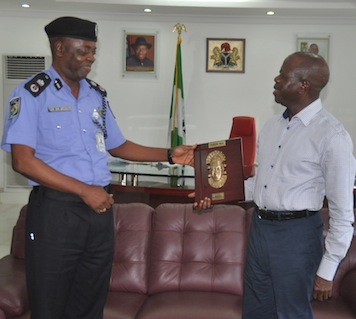Governor Adams Oshiomhole of Edo State presents a souvenir to Mr Samuel Adegbuyi, new Commissioner of Police, Edo State during the Police Commissioner's visit to the Governor