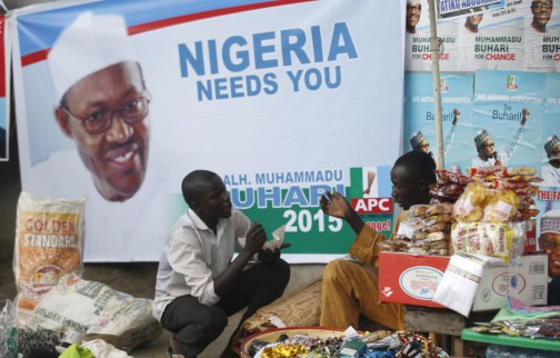 Vendors sell their wares near a Buhari poster