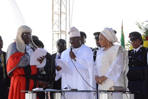 Oyo State Chief judge , justice  Munta Ladapo Abimbola administering oath of office to Governor Ajimobi and  the wife, Florence watching in admiration