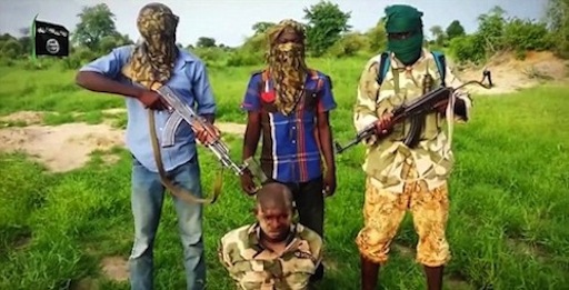 A Nigerian soldier is made to kneel in front of three militants after he was captured by Boko Haram