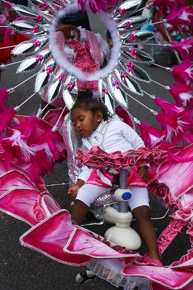 A young child sleeps in a flamboyantly decorated buggy during a parade on the first day of the Notting Hill Carnival in west London on August 30, 2015 (AFP Photo/Niklas Halle'n)