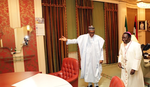 President Muhammadu Buhari ushers Bishop Mathew Hassan Kukah to the table