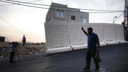 A television crew films as a Palestinian man walks past a wall put in place by Israeli officials to separate the Palestinian neighborhood of Jabel Mukaber from the Jewish settlement of Armon Hanatziv in east Jerusalem, on October 18, 2015 (AFP Photo/Thomas Coex)
