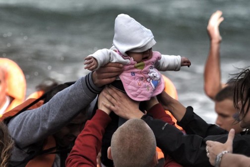 A baby is handed to safety as migrants arrive on the Greek island of Lesbos on October 31, 2015 (AFP Photo/Aris Messinis)