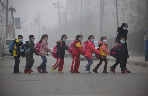 Schoolchildren cross the street in Jinan, in east China's Shandong province on December 24, 2015 amid heavy air pollution (AFP Photo)