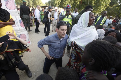 Former UK Foreign Secretary David Miliband, centre, kneels as he listens to children singing "ABC" displaced by Boko haram attacks, in a camp in Maiduguri, Nigeria,  Monday, Dec. 7, 2015, in the heart of Nigerias war zone.  Miliband, now president of the International Rescue Committee, dropped to kneel to make eye contact with children in a refugee camp Maiduguri, the northeastern city that has 1 million residents and 2 million refugees, half of them children. (AP Photo/Sunday Alamba)