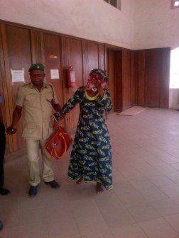 Court Registrar, Oluronke Rosolu covering her face while being led in court by a prison official on Monday, 21 Dec., 2015