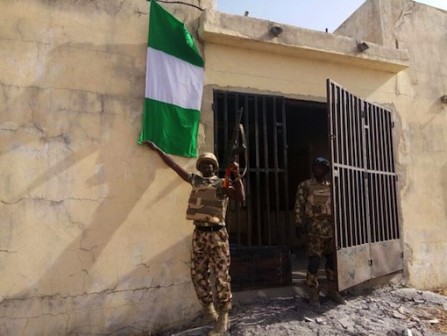 Nigerian troops hoist a Nigerian flag after reclaiming Kala Balge