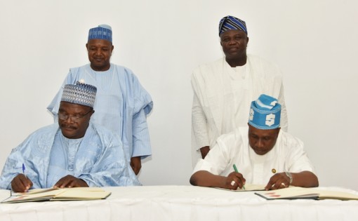 Lagos State Commissioner for Agriculture, Mr. Oluwatoyin Suarau (right), with Permanent Secretary, Kebbi State Ministry of Agriculture, Dr. Nababa Adamu (left), signing a Memorandum of Understanding on the Development of Commodity Value Chains between the two States while Lagos State Governor, Mr. Akinwunmi Ambode (right behind) and Kebbi State Governor, Alhaji Atiku Bagudu (left behind) watch, at the Lagos House, Ikeja, on Wednesday, March 23, 2016.