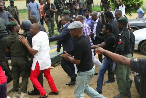 Minister of Transportation, Rotimi Amaechi (in purple and white check shirt) surrounded by security operatives as he arrives the venue