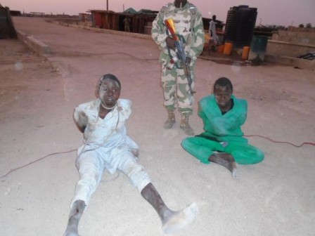 Nigerian soldier stand behind paraded Boko Haram members