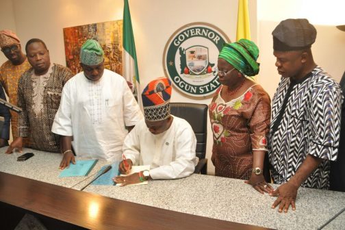 Governor Ibikunle Amosun, signing the law creating the 37 new LCDAs in the presence of the Speaker, Ogun State House of Assembly, Suraj Ishola Adekunbi (left), Deputy Governor, Chief (Mrs.) Yetunde Onanuga (right) while other top government functionaries look on.